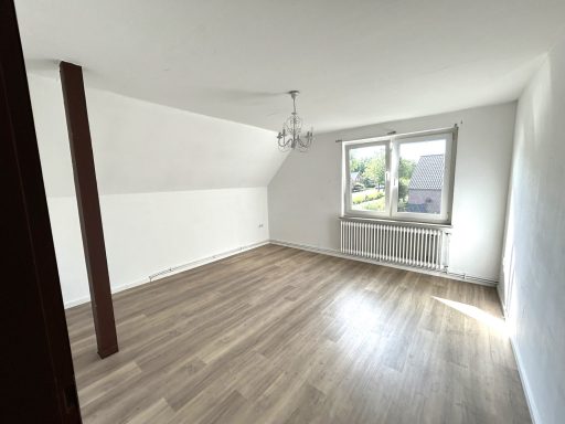 Heller, leerer Raum mit Holzfußboden und einem Fenster.